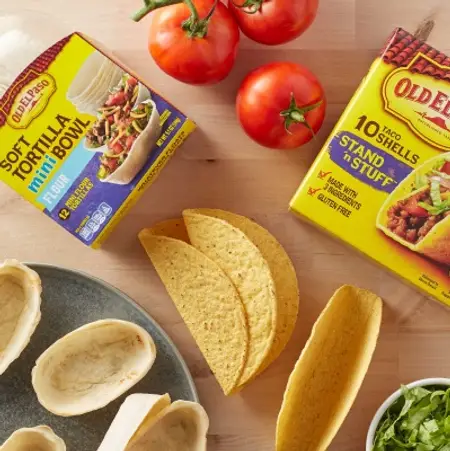Old El Paso Shells & Tortillas on a wooden table with three tomatoes 